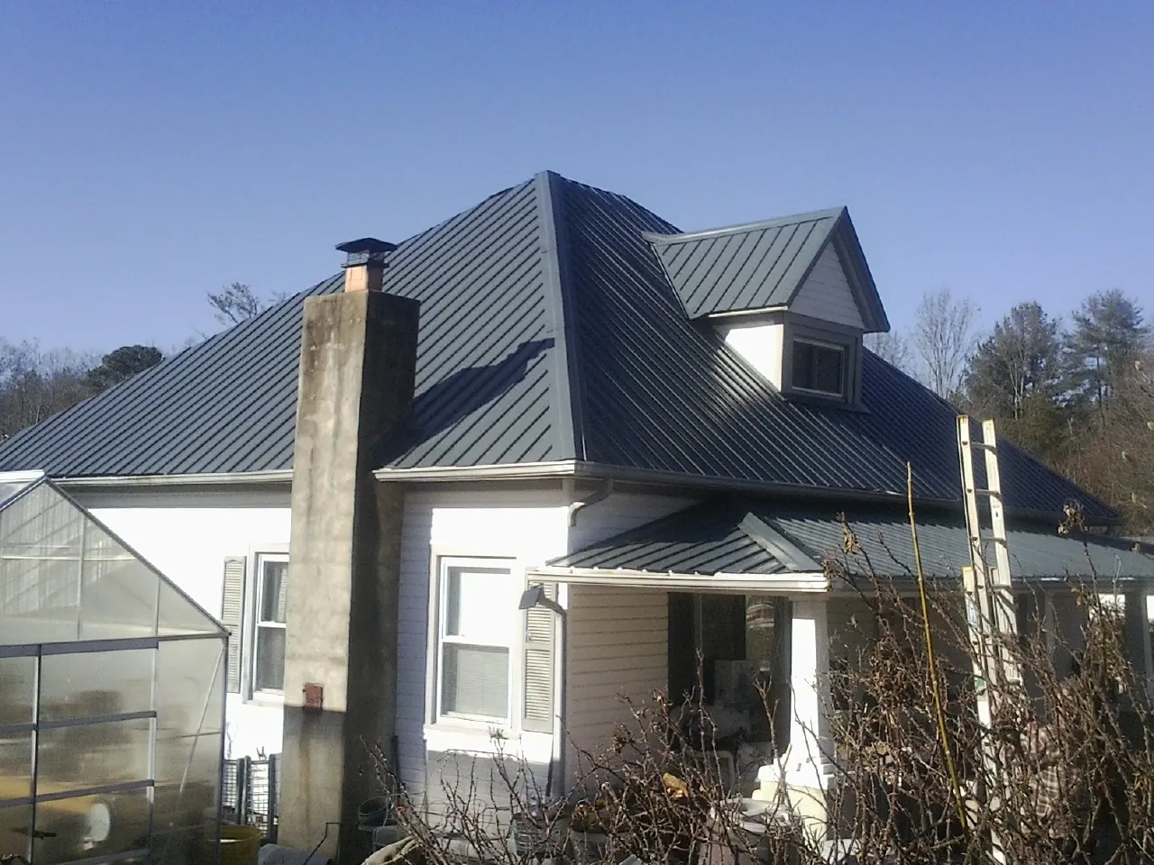 Dark blue standing seam metal roof on a white farmhouse with dormer — Slate & Tile Roof Repair by Roofing Brothers in Lake Hughes