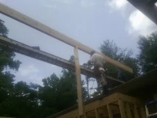 Carpenter setting a ridge beam over a new addition frame — Ice Dam Removal by Roofing Brothers in Lake Hughes
