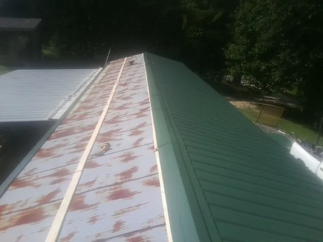 Old rusted panels beside newly installed green metal roofing — Wind Damage Roof Repair by Roofing Brothers in Lake Hughes