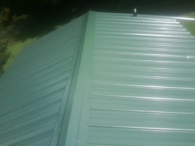 New green metal panels meeting at the ridge of a roof — Flat Roof Repair work by our crew in Lake Hughes