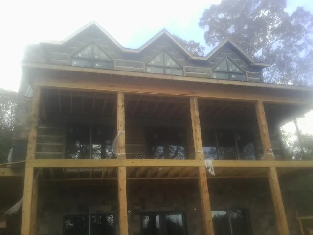 Dormers and porch framing on a large log home under construction — Roof Coating work by our crew in Lake Hughes
