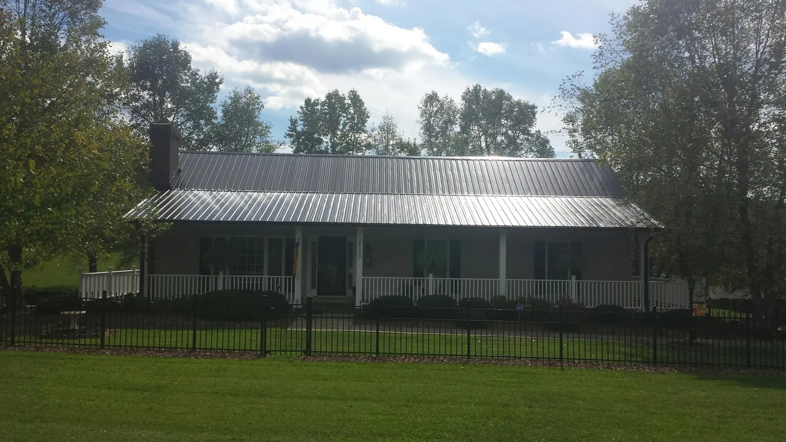 Gray metal roof on a brick ranch with a full width front porch — Gutter Guard Installation work by our crew in Lake Hughes