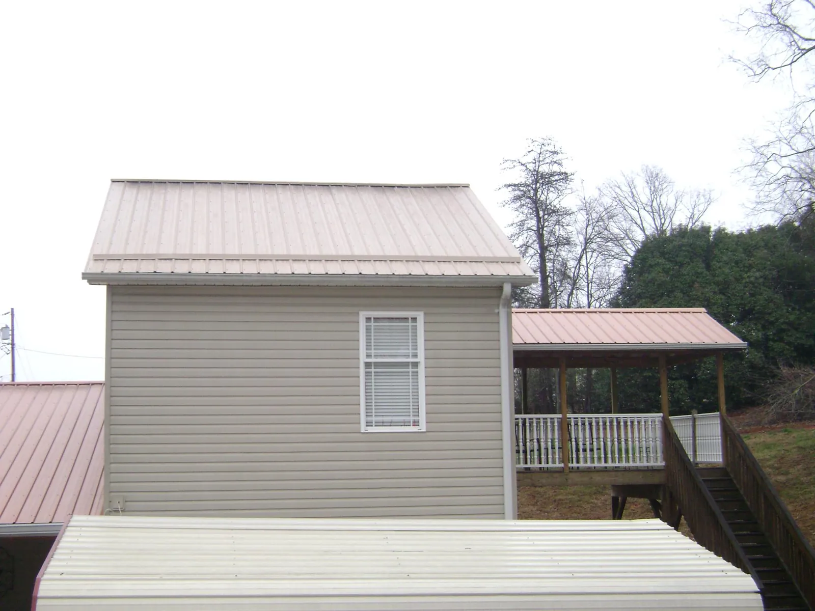 Tan metal roofs on a two story addition and attached porch, from a Roof Replacement job in Lake Hughes