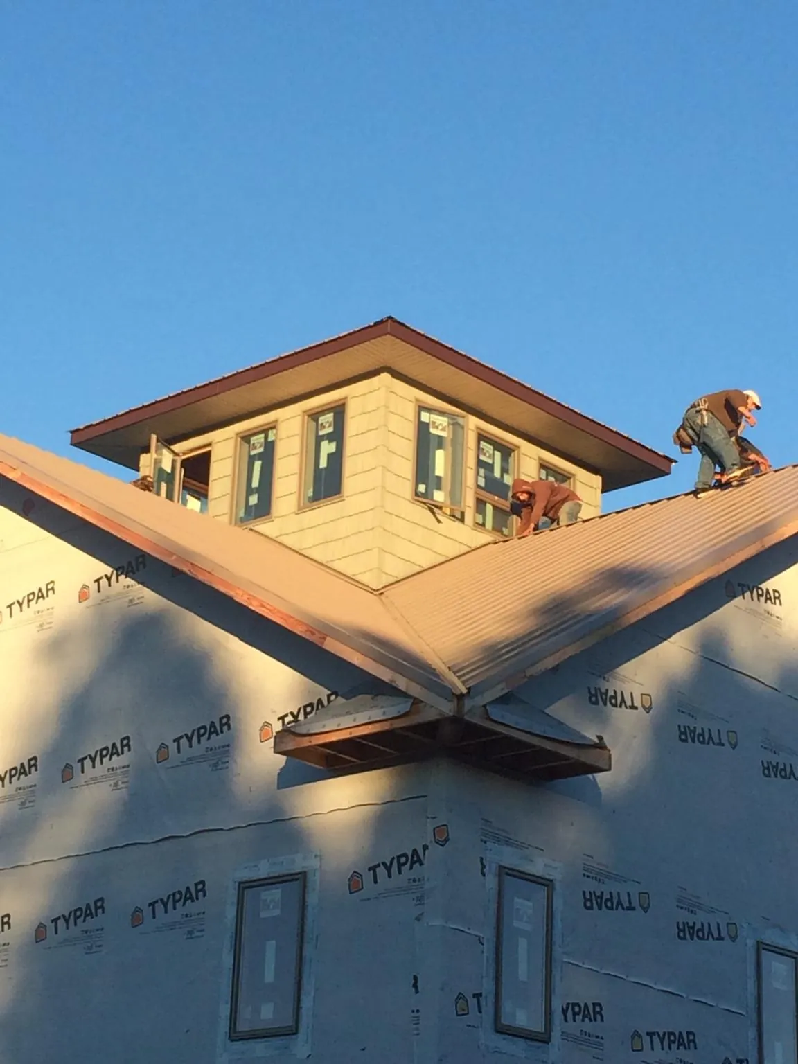 Roofers working around a rooftop cupola on a new metal roof at sunset — Roof Waterproofing in Lake Hughes by Roofing Brothers